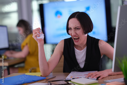Foto Annoyed female office worker crumples report after noticing mistake