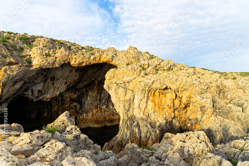 Natural rock archway carved by the sea, revealing a dark cave entrance