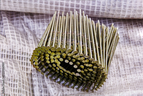 Foto Coil of collated nails connected by wire, fasteners for pneumatic nail gun use in construction and woodworking
