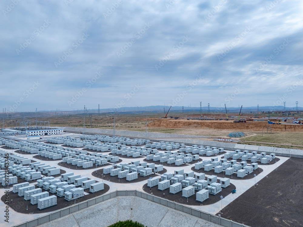 Naklejka premium Large scale outdoor energy storage power station with neatly arranged battery modules under cloudy sky