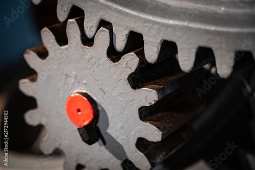 Close-up of old heavy industrial spur gears meshing together, showing a pinion gear engaged with a large ring gear made of cast iron.