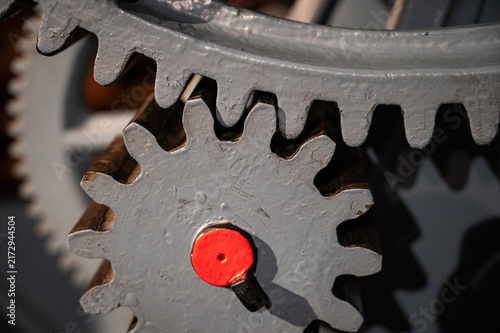 Close-up of old heavy industrial spur gears meshing together, showing a pinion gear engaged with a large ring gear made of cast iron.