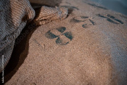 Close-up of the rough woven texture of an old burlap cargo sack featuring stenciled identifying numbers printed with black paint.