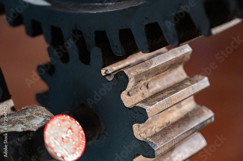 Close-up of old heavy industrial spur gears meshing together, showing a pinion gear engaged with a large ring gear made of cast iron.
