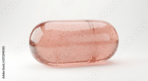 Macro of Translucent Pink Softgel Capsule with Liquid and Bubbles on White Background