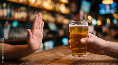 Man refusing beer glass with stop hand gesture at bar