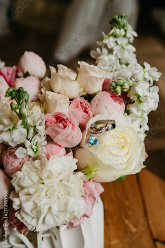A bouquet of various and colorful flowers with two wedding rings lying on it on the wedding day for the bride and groom
