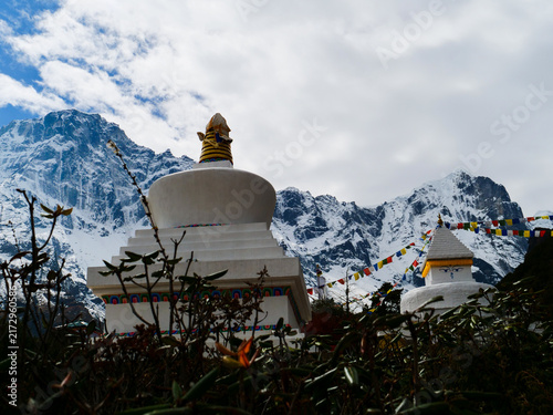 Photography White stupas with prayer flags and snow-capped mountains in the Himalayas, Nepal