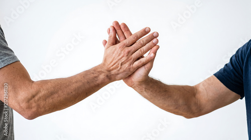 Close up of two hands touching in a high five gesture against a simple background, representing teamwork, unity, cooperation, partnership and mutual support.