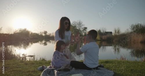 Family rest near Lake. Young mother spend time with children son and daughter enjoying nature. 4K 10-bit