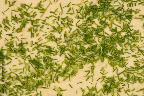 Photography A high angle full frame view of a thick layer of finely chopped green chives scattered across the surface of fresh raw pastry dough