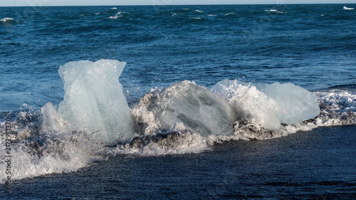 Foto Melting ice fragments from Vatnajokull Glacier float along the black sand coast of Diamond Beach in Iceland, with multiple ice pieces shaped by waves and ongoing glacial melt