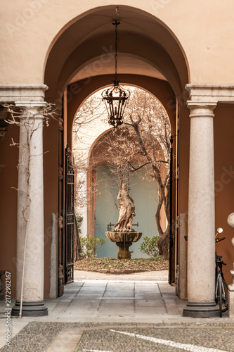 Decorative fountain with statue of a young woman and dog in the courtyard of Palazzo Borromeo d'Adda, Milan, Italy