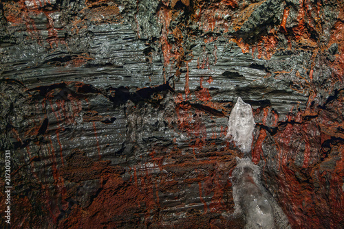 Fotografie Lava forms contorted grey folds around pale ice inside Raufarholshellir, Iceland