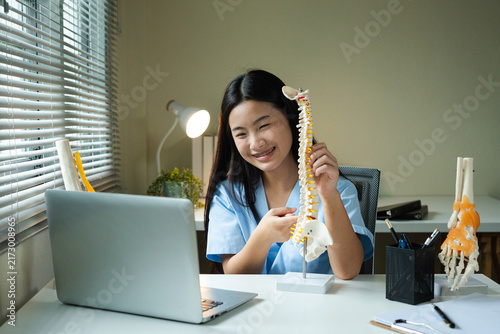 Bild auf Leinwand Teenage Girl in Medical Scrubs Holding Spine Model During Virtual Work Experienc