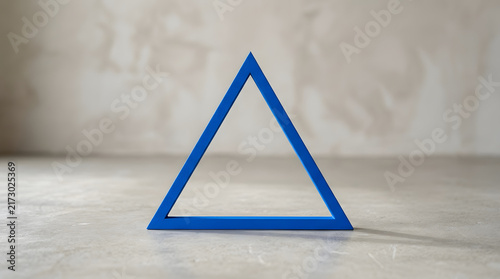 Blue triangular frame standing on concrete surface with blue triangle