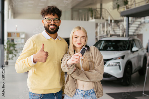 Diverse couple celebrating new car ownership at dealership