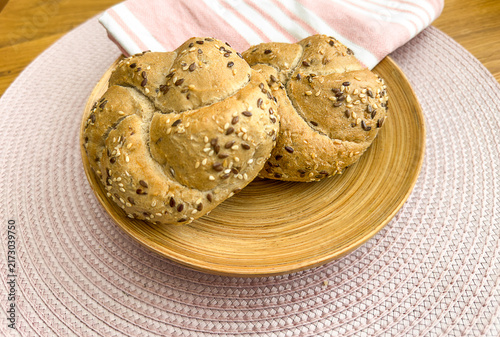 Foto Seeded Kaiser rolls with sesame flax multigrain bread buns served on wooden plat