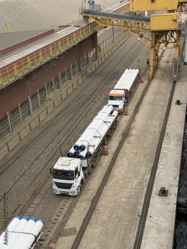 фотографія seaport wharf heavy trucks deliver big diameter pipes.