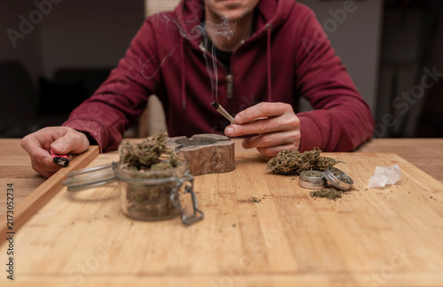 Fotografía lose up of man sitting at table while smoking cannabis