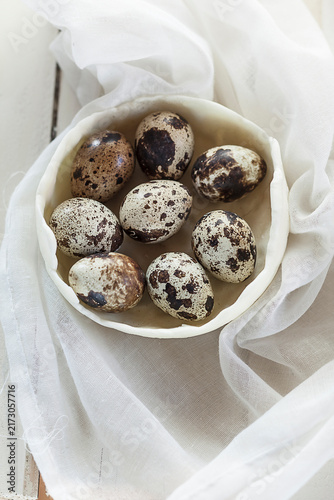 Bowl of quail eggs on white cloth and wood