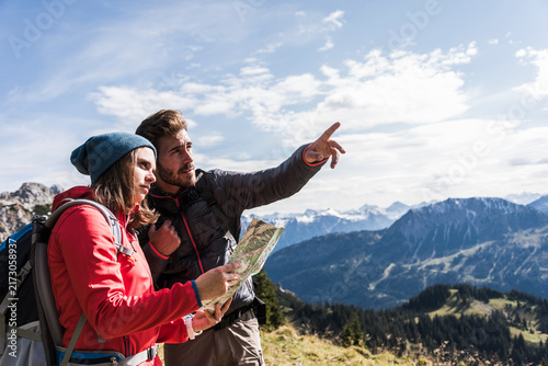 Austria, Tyrol, young couple with map in mountainscape looking around