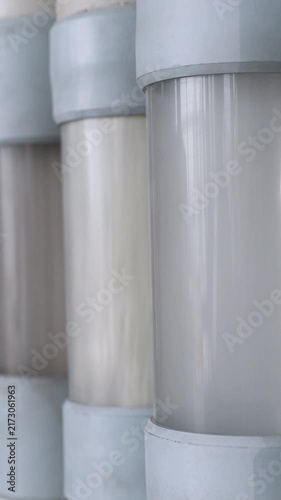 Vertical video. Close up view of flour moving through transparent pipes in a pneumatic conveyor system, part of the automated production line at a contemporary industrial milling facility