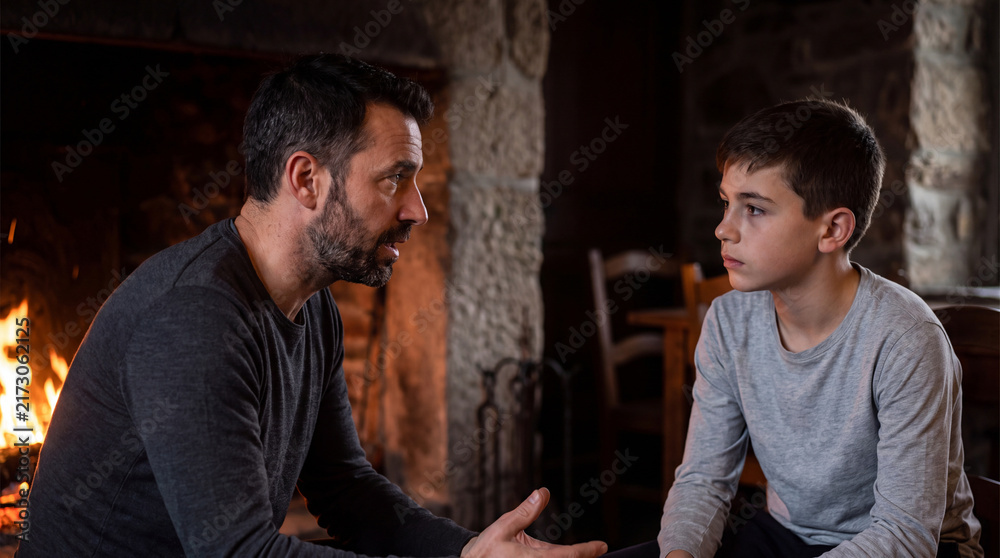 Obraz premium Adult talking with teenage boy by fireplace