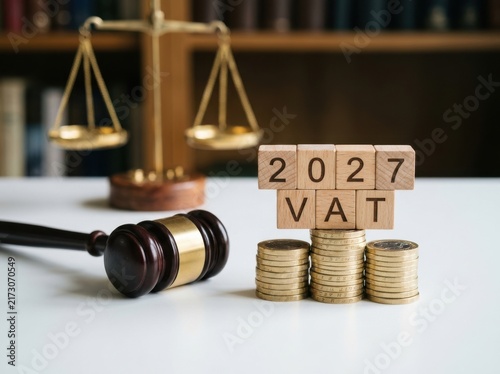 Wooden blocks with the text 2027 vat placed on stacks of gold coins with a judges gavel and scales of justice in the background