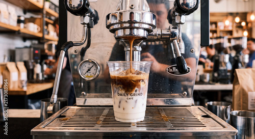 Espresso Machine Pouring Fresh Coffee Layer into Iced Milk in Clear Plastic Cup on Drip Tray