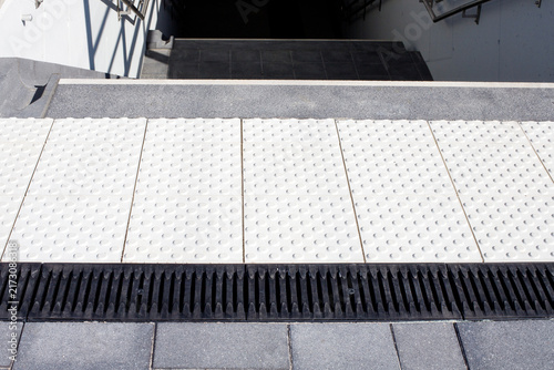 Tactile Paving Tiles and Drainage Grates Before Staircase Exit at Station