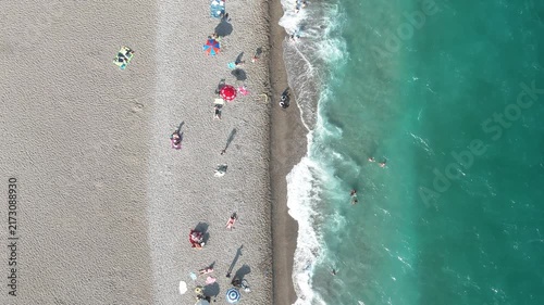 Aerial view of sunbathing people at the beach of turquoise sea 
