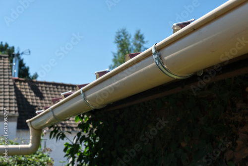 Fotografie Galvanized steel gutter fixing bracket mounted on corrugated metal roofing for rainwater drainage installation