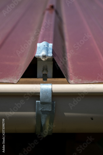 Canvastavla Galvanized steel gutter fixing bracket mounted on corrugated metal roofing for rainwater drainage installation