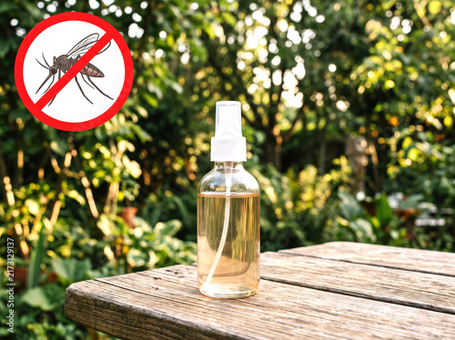 Mosquito repellent spray bottle on a wooden table in a garden with a no mosquito sign. Suitable for ads, product packaging, pest control promotions, blogs, banners, preventive care, and e-commerce.