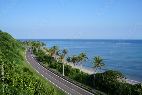 Aerial view of scenic tropical coastal highway curving along turquoise ocean shoreline