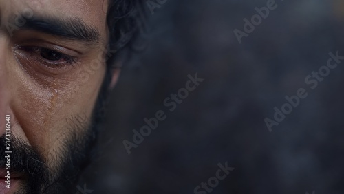 Close-up of crying man with tear on cheek. Biblical scene of Peter weeping after betrayal of Jesus. Repentance, sorrow and forgiveness concept. Holy week and Easter story.