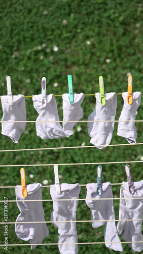 White socks hanging on clothesline with colorful clothespins drying in sunny garden