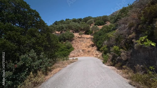 A car drives slowly along a dangerous winding mountain road on the island of Crete, Greece.