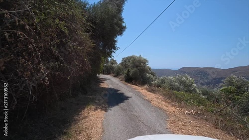 A car drives slowly along a dangerous winding mountain road on the island of Crete, Greece.