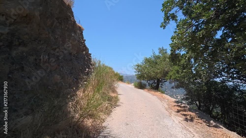 A car drives slowly along a dangerous winding mountain road on the island of Crete, Greece.