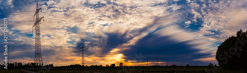 Sunset with a dramatic sky and overland high voltage lines soon to be replaced by Ostbayernachse near Tabertshausen, Aholming, Deggendorf, Bavaria, Germany