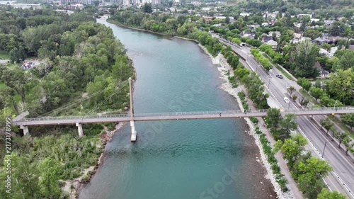flying backwards above Bow River next to Prince’s Island Park, away from Bow River Pathway Bridge, located next to Downtown Calgary ( Alberta, Canada) - 4k aerial video footage 