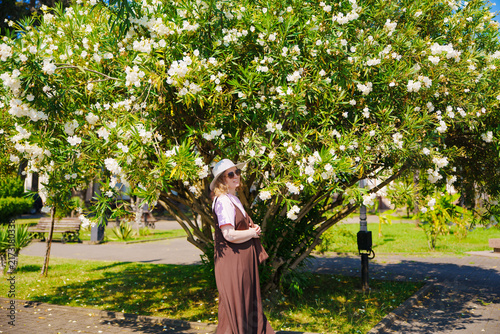 Woman in Hat Standing Under Blooming White Oleander Tree