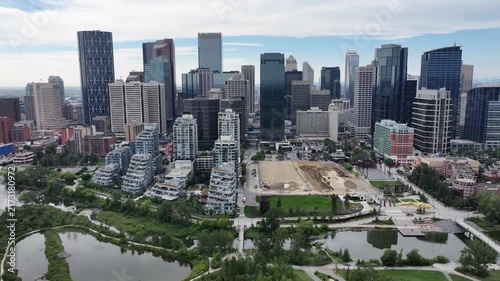 flying along Skyline of Downtown Calgary ( Alberta, Canada) and panning left  to Centre St Bridge, with Prince’s Island Park and Bow River below - 4k aerial video footage 