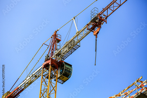 Bild auf Leinwand Tower crane with operator cabin and hook against clear sky at construction site,