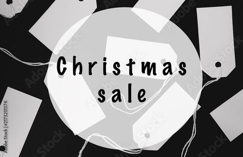Black and white image featuring Christmas sale tags scattered on a black background, emphasizing holiday shopping and discounts.