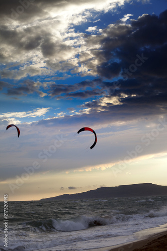 Two silhouette of power kites at sunset sky