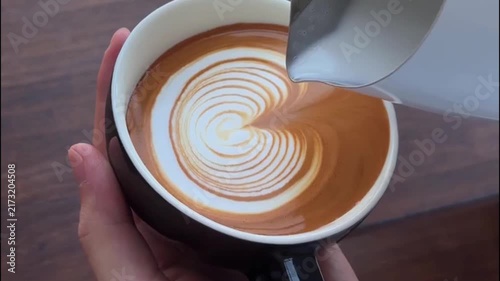 Barista Pouring Steamed Milk into Black Cup to Create Flower Latte Art