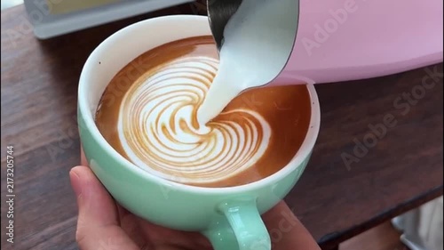 Barista Pouring Steamed Milk into Light Green Cup to Create Swan Latte Art